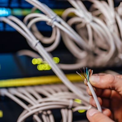 Male hand holding stripped wires of ethernet cable, close-up.