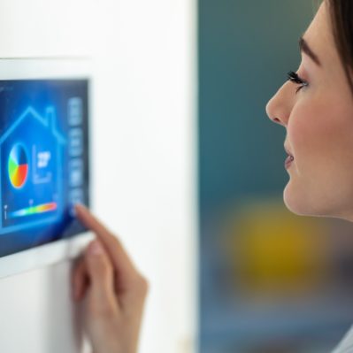Pretty young woman using the home automation system on digital tablet to regulate the temperature.