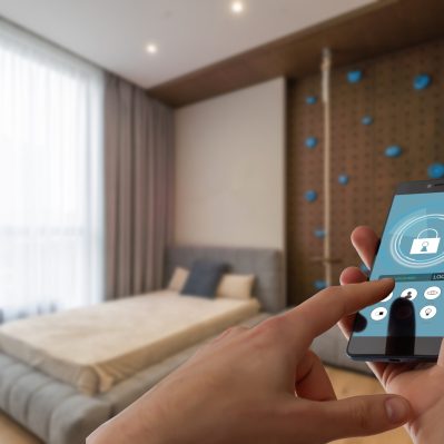 Smart home automation app on smartphone hold by female hand with home interior in background